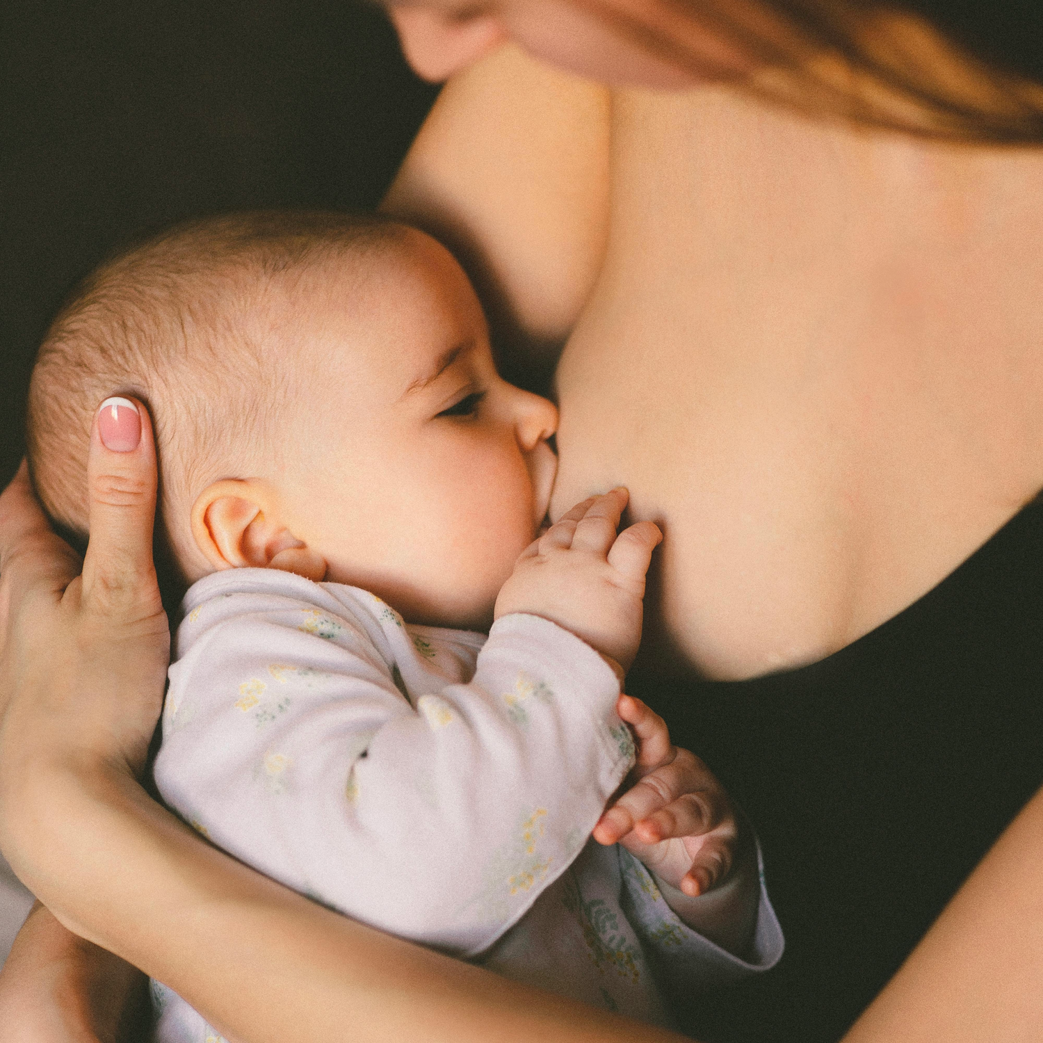 Mutter stillt ihr Baby in inniger Umarmung – natürliche Ernährung, Bindung beim Stillen, Säugling erhält Muttermilch.