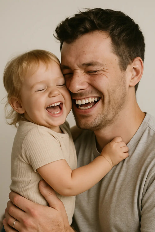 Vater hält lachendes Kleinkind im Arm, Symbolbild für Wonder Kinderwunsch Mann Nährstoffe und männliche Fruchtbarkeit.