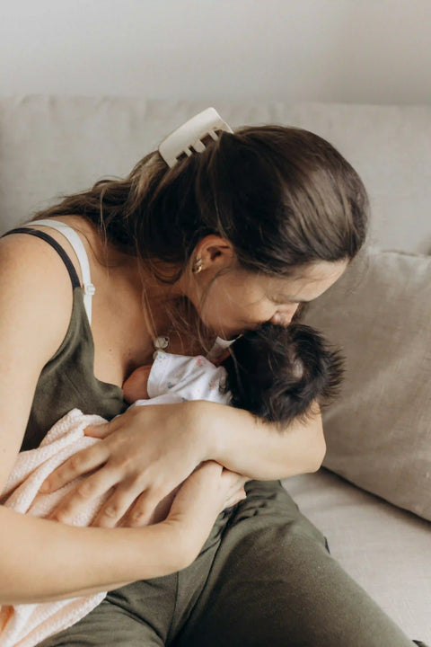 Mutter stillt ihr Neugeborenes liebevoll auf dem Sofa, Kundenfoto zur Rezension des Wonder Stillzeit Produkts.